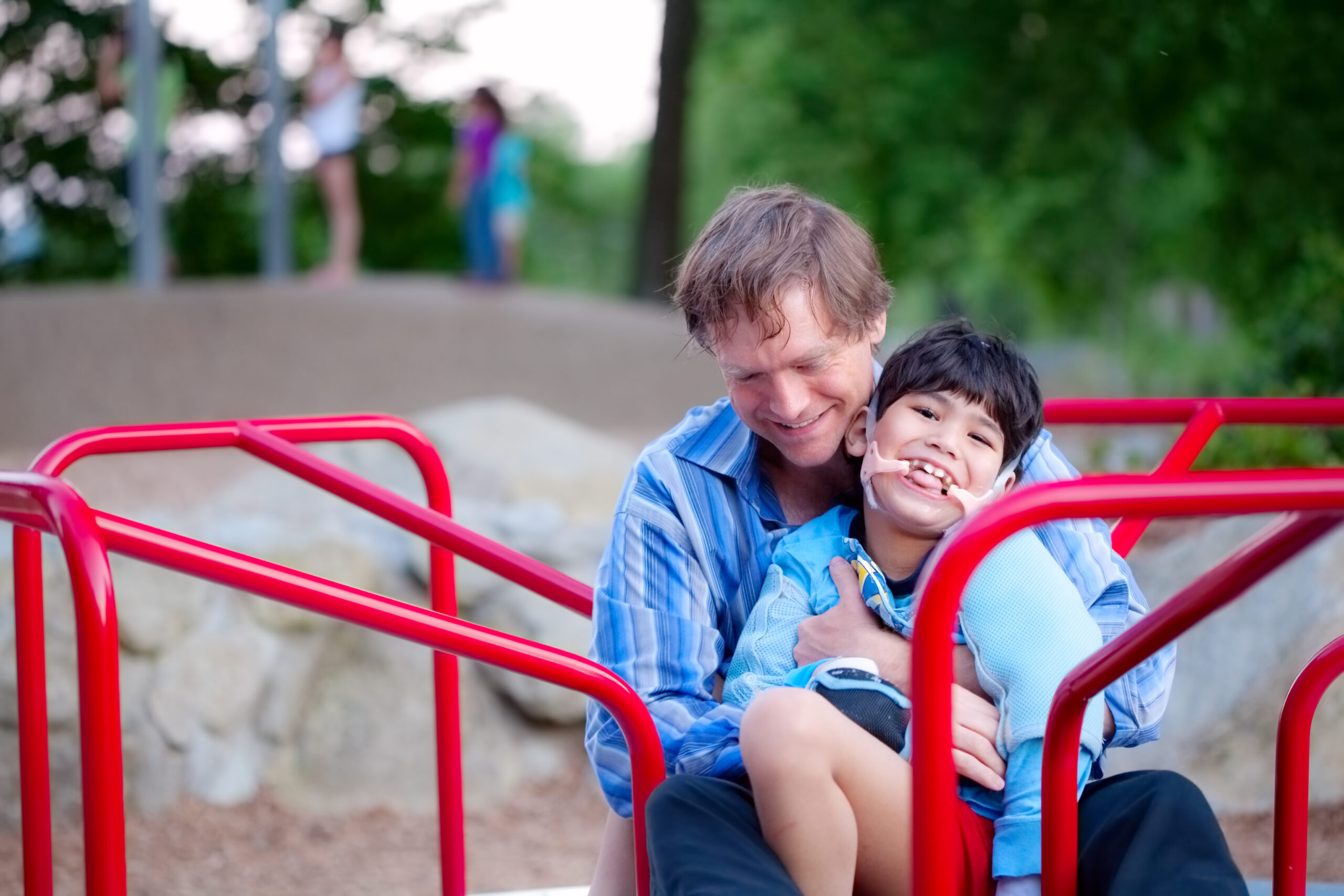 Caregiver father at park with intellectually disabled son.