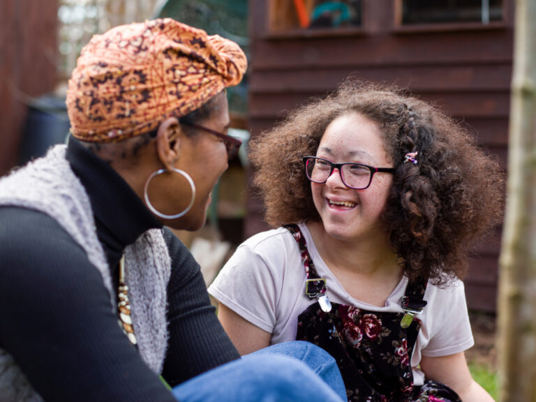 Mom and developmentally disabled daughter sitting, talking and enjoying their backyard.