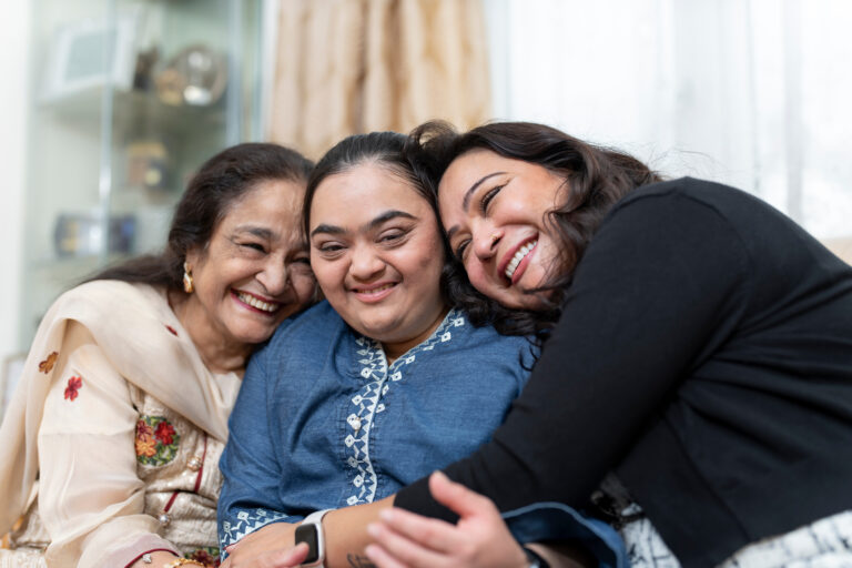 Grandmother and mother share a hug with granddaughter with developmental disabilities.