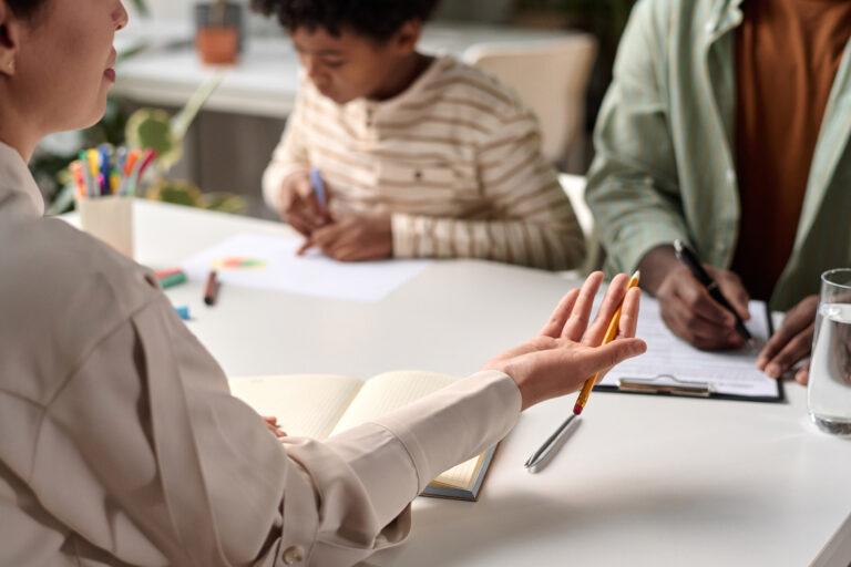 Care coordinator discussing care plan with parent caregiver while child colors at table.