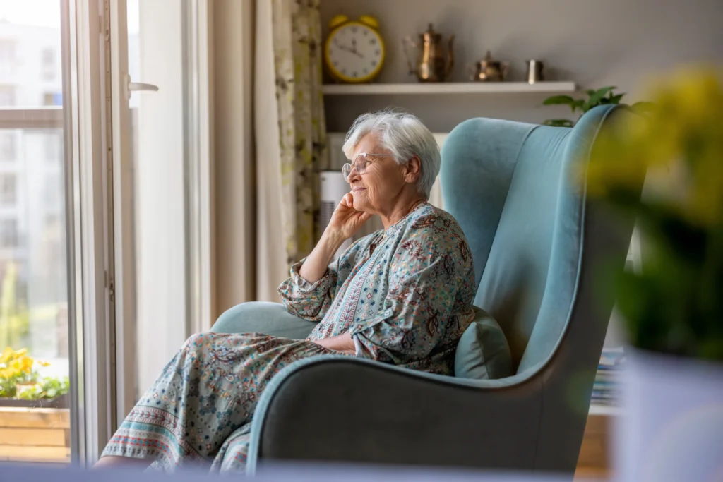 Smiling older woman sitting in a chair gazing out the window
