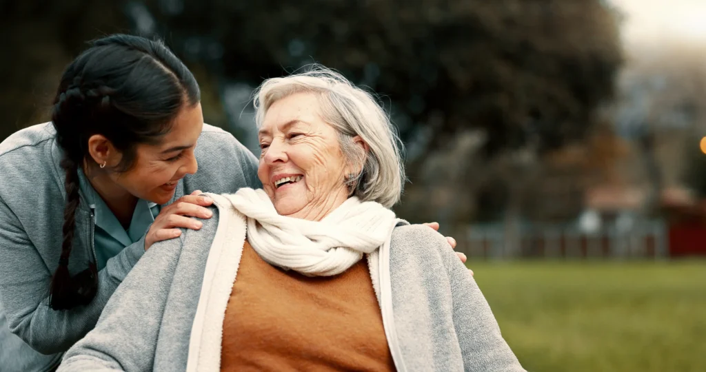 Caregiver woman holding the shoulders of an elderly woman who is sitting down